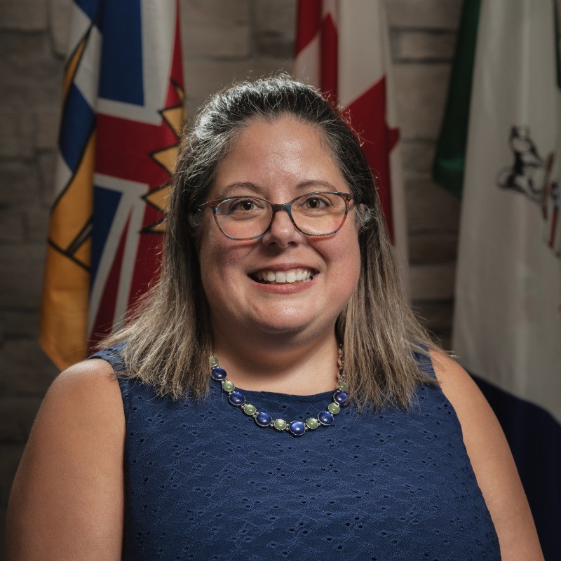 Amber Stewart is a Director at Large at the PABC Board. She is standing in front of the British Columbian and Canadian flags.